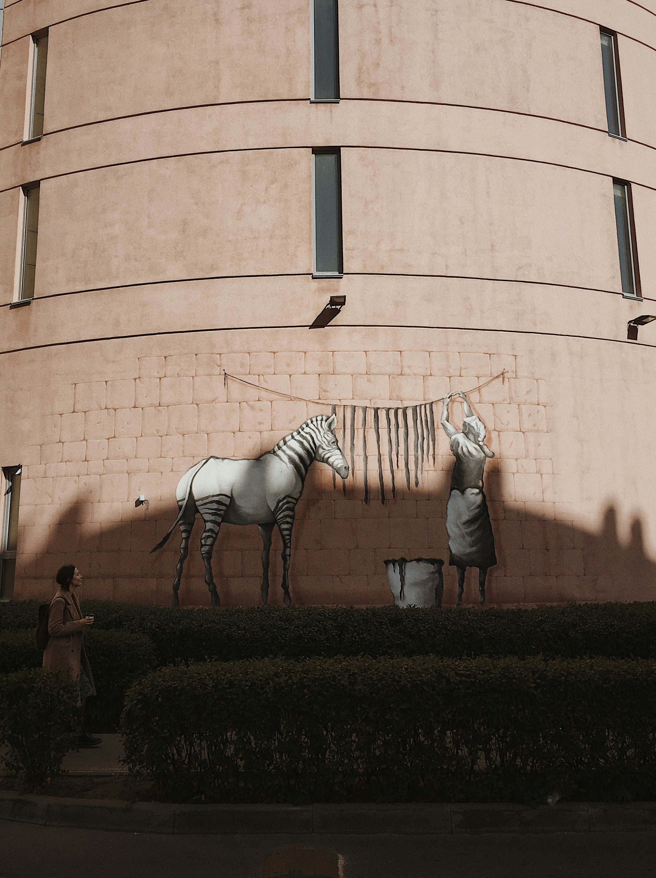 woman in white and black stripe long sleeve shirt standing beside brown concrete building during daytime